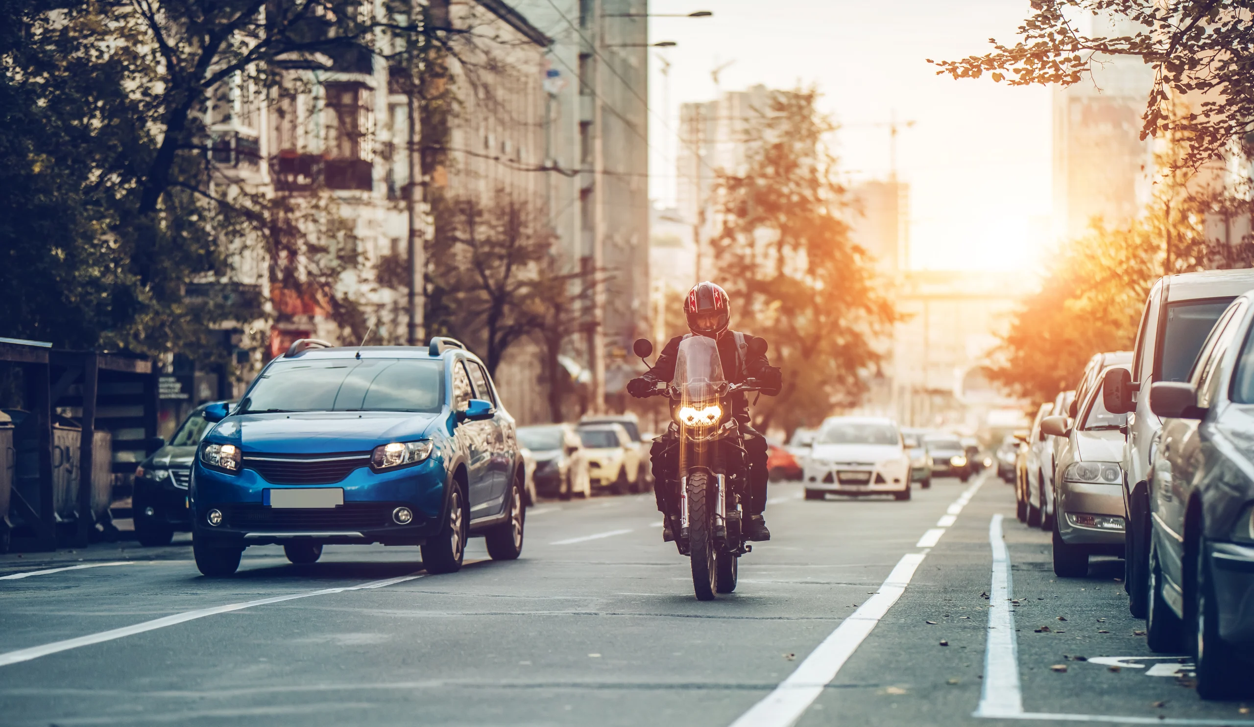 Motorcycle driving down a road between cars