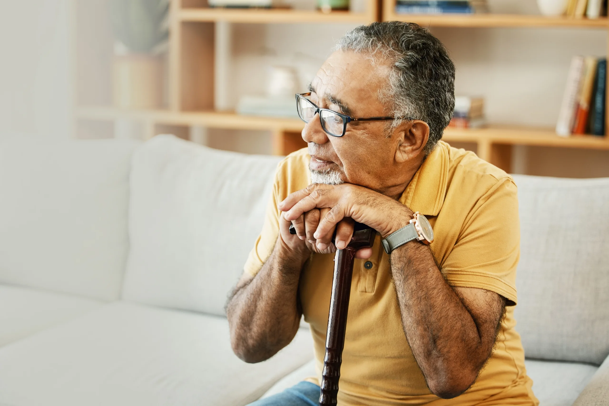older man resting his head on his cane